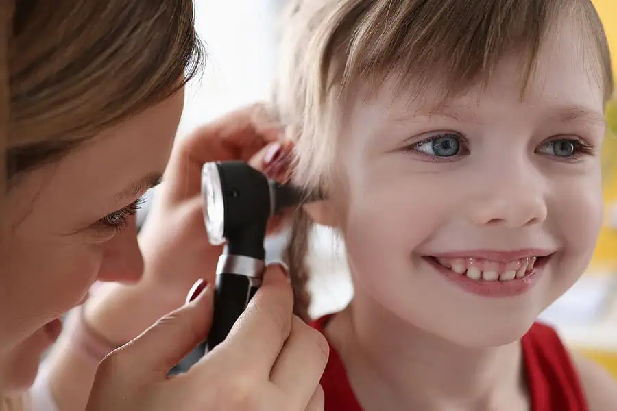 Young girl undergoing an examination by a  paediatrician using an otoscope